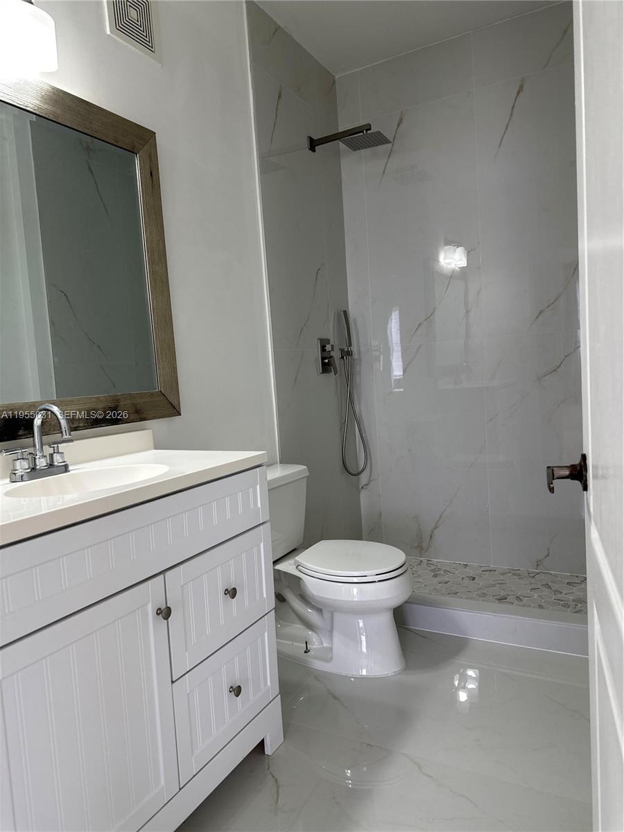 7090 Northwest 177th Street, Unit 1009 Hialeah, FL 33015 - Photo 7 of 9 a bathroom with a toilet sink and mirror