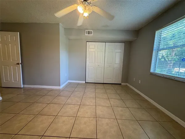an empty room with windows and ceiling fan