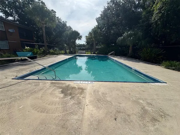 a view of backyard with swimming pool and seating space