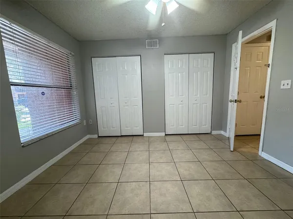 an empty room with windows and fan