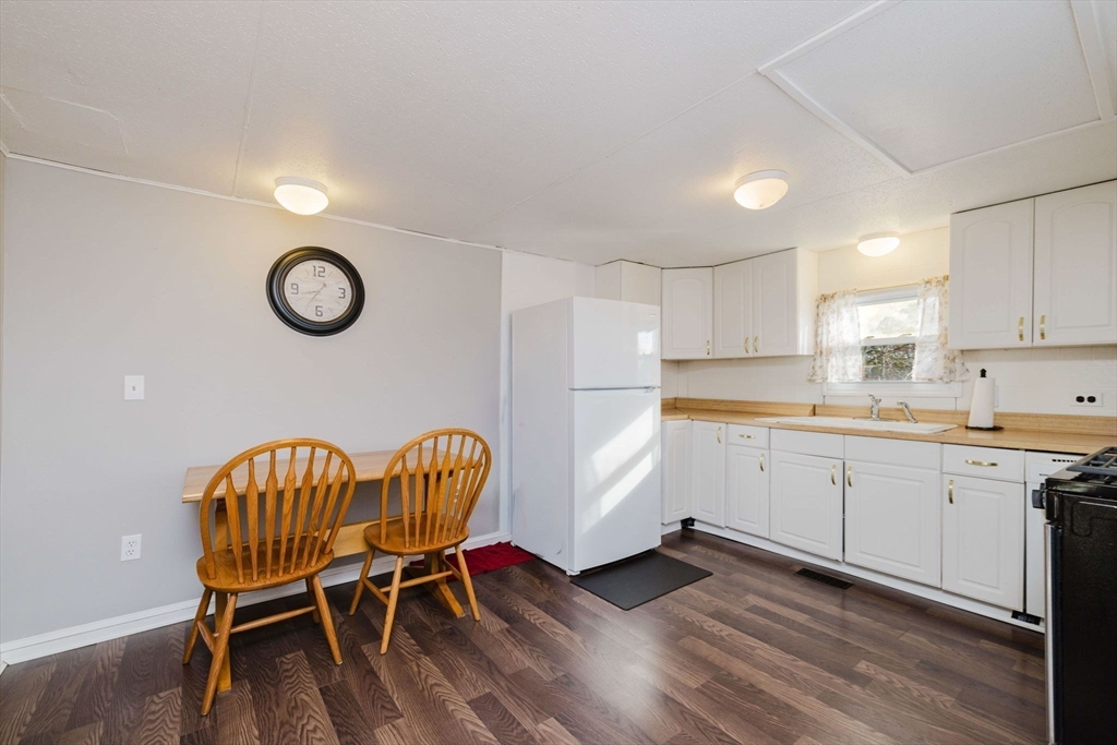 3040 Cranberry Highway, Unit 41 Wareham, MA 02538 - Photo 7 of 25 a kitchen with a table chairs a sink dishwasher and a stove with wooden floor