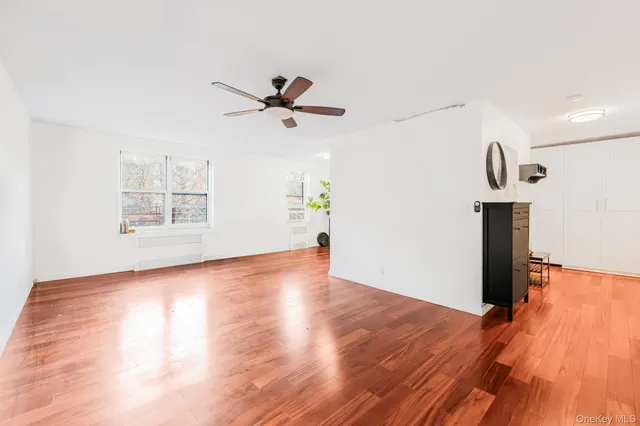 a view of empty room with wooden floor and fan