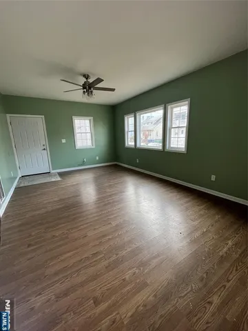 an empty room with wooden floor chandelier and windows