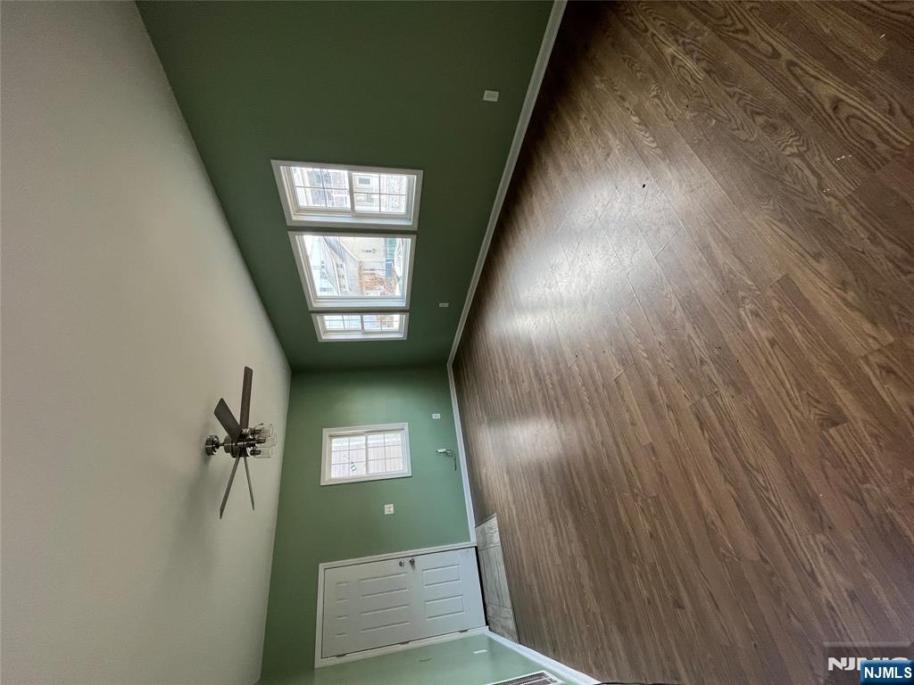an empty room with wooden floor chandelier and windows