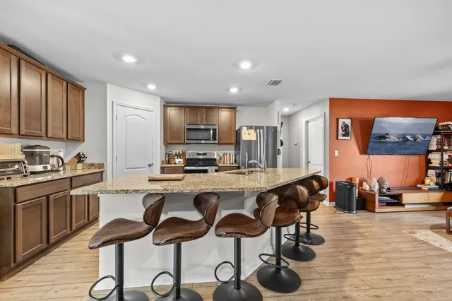 a kitchen with stainless steel appliances granite countertop a stove top oven a sink a refrigerator cabinets and dining table