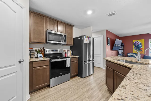 a kitchen with granite countertop wooden floors stainless steel appliances and center island