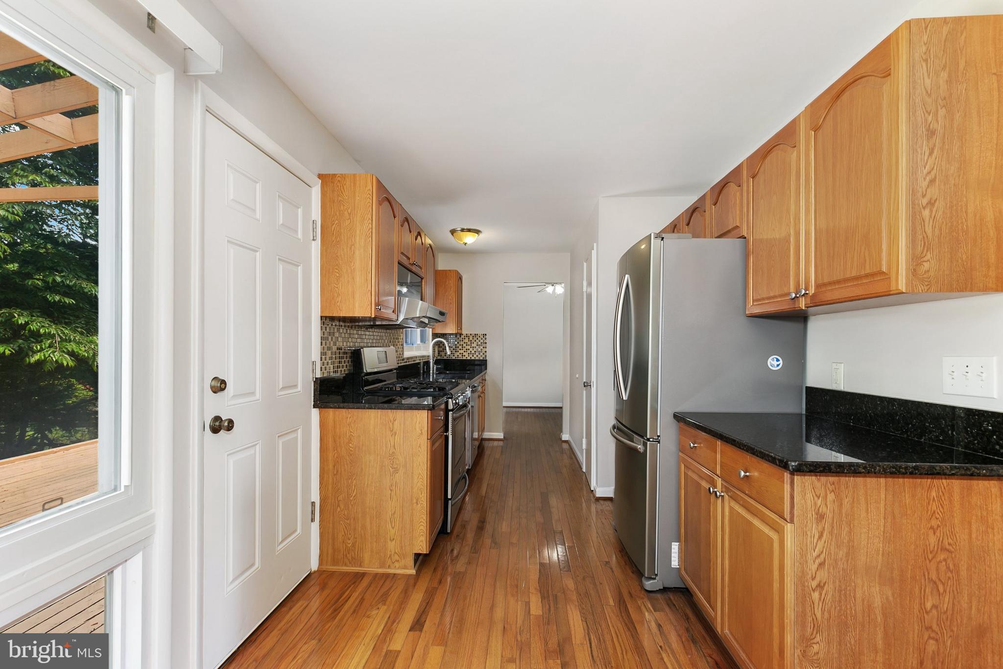 11501 Piney Lodge Road North Potomac, MD 20878 - Photo 11 of 64 a kitchen with granite countertop a refrigerator a sink a stove and white cabinets with wooden floor