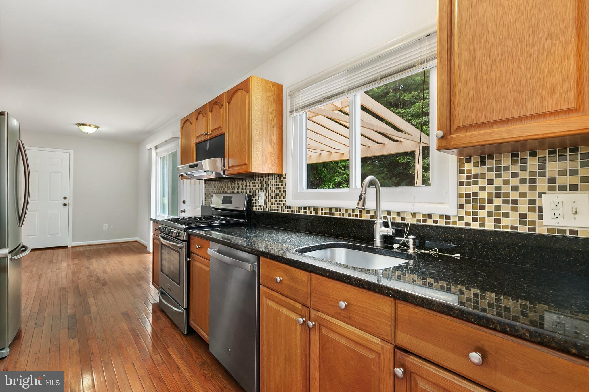 11501 Piney Lodge Road North Potomac, MD 20878 - Photo 15 of 64 a kitchen with stainless steel appliances granite countertop a sink a stove and a wooden floor
