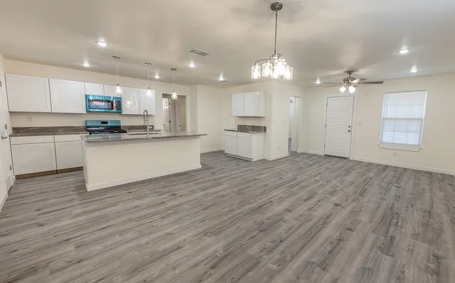 a view of a kitchen with granite countertop wooden floor stainless steel appliances and a chandelier