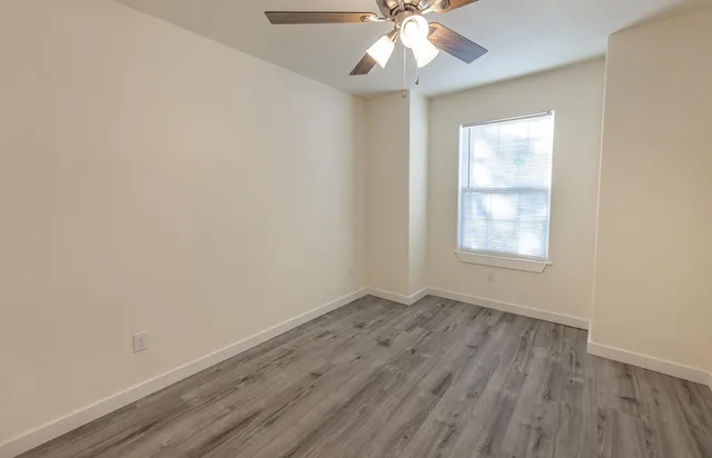 an empty room with wooden floor and a ceiling fan