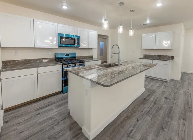a kitchen with stainless steel appliances granite countertop a stove a sink and a microwave