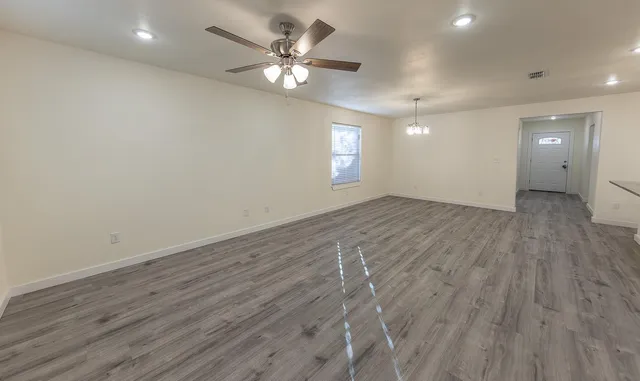 an empty room with wooden floor and window