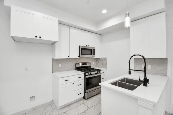 a kitchen with white cabinets and appliances