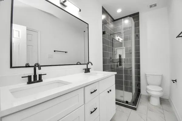 a bathroom with a double vanity sink toilet and shower