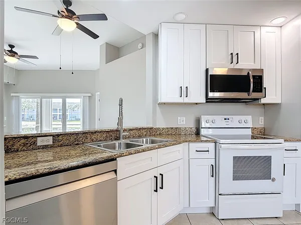 a kitchen with granite countertop a sink a stove and microwave