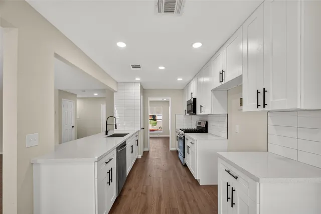 a large kitchen with stainless steel appliances lots of counter space and wooden floor