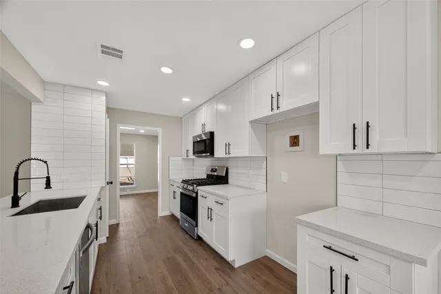 a kitchen with white cabinets and stainless steel appliances