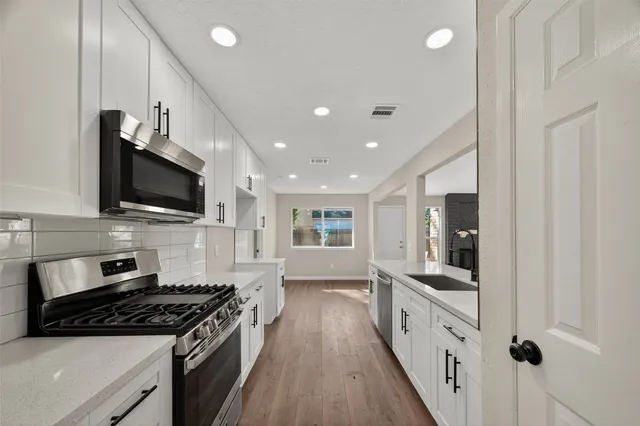 a large kitchen with stainless steel appliances granite countertop a stove a sink and a refrigerator