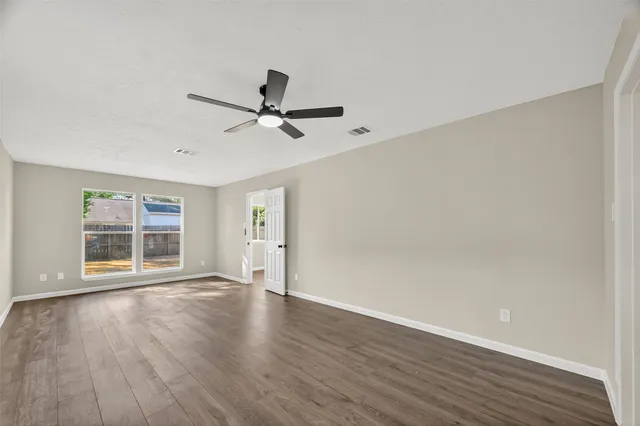 a view of an empty room with a window and wooden floor