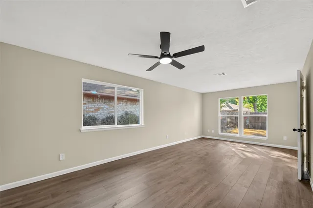 a view of an empty room with a window and wooden floor