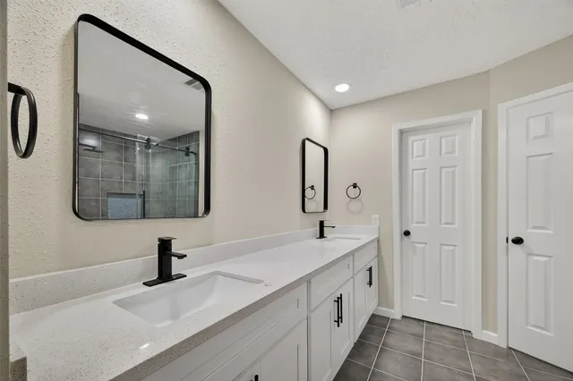 a spacious bathroom with a double vanity sink a mirror and shower
