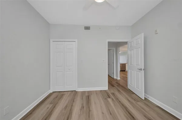 a view of empty room with wooden floor and fan