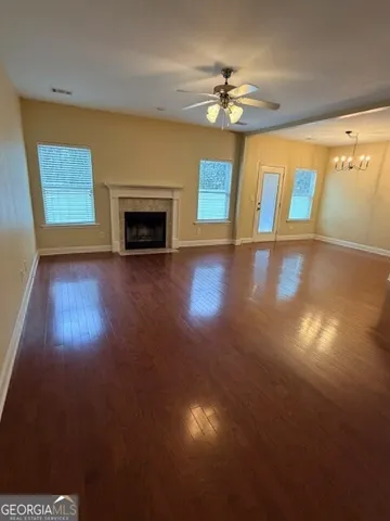 a view of an empty room with a fireplace and wooden floor