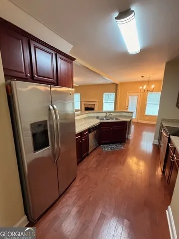 a kitchen with stainless steel appliances granite countertop a refrigerator a stove and a sink with wooden floors