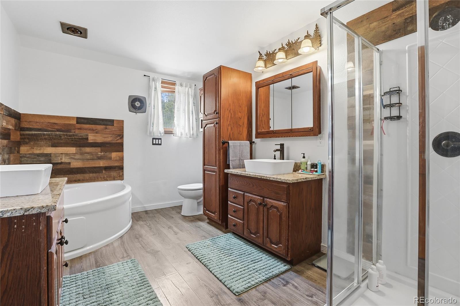 9225 Sandy Lane Conifer, CO 80433 - Photo 16 of 45 a bathroom with a double vanity sink a toilet a mirror and shower