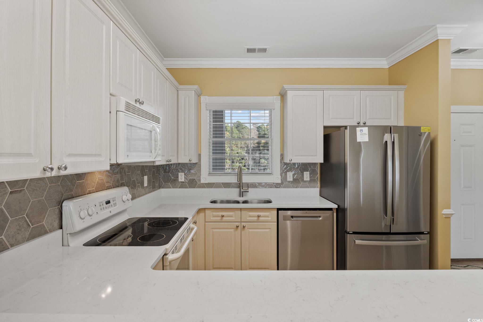 4847 Luster Leaf Circle, Unit 403 Myrtle Beach, SC 29577 - Photo 12 of 37 Kitchen with stainless steel appliances, tasteful backsplash, light stone countertops, and crown molding