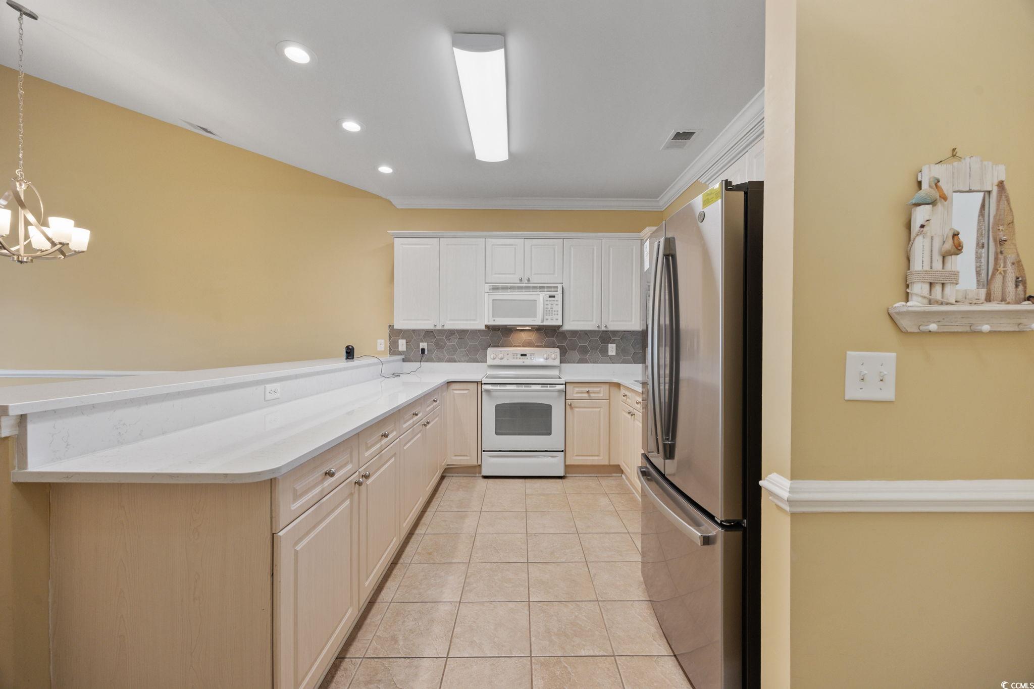 4847 Luster Leaf Circle, Unit 403 Myrtle Beach, SC 29577 - Photo 14 of 37 Kitchen featuring white appliances, decorative backsplash, light tile patterned floors, decorative light fixtures, and recessed lighting