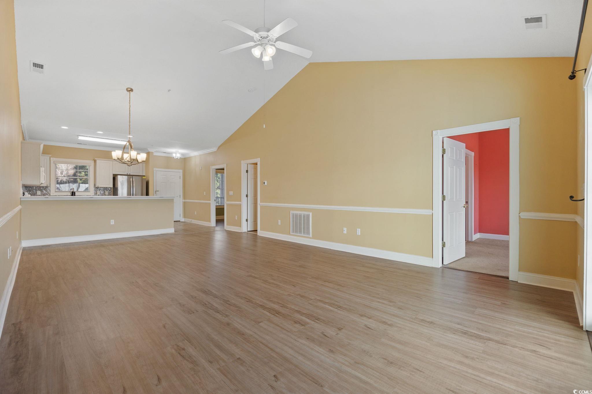 4847 Luster Leaf Circle, Unit 403 Myrtle Beach, SC 29577 - Photo 7 of 37 Unfurnished living room featuring light wood finished floors, a chandelier, ceiling fan, and high vaulted ceiling