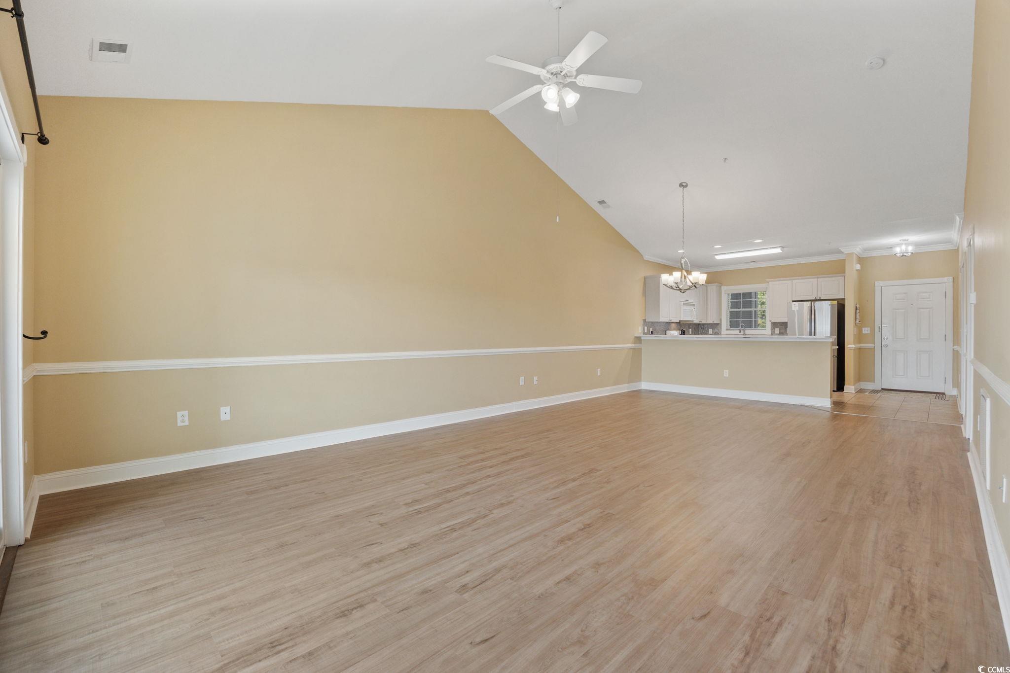 4847 Luster Leaf Circle, Unit 403 Myrtle Beach, SC 29577 - Photo 8 of 37 Unfurnished living room featuring light wood-type flooring, ceiling fan, a chandelier, and high vaulted ceiling