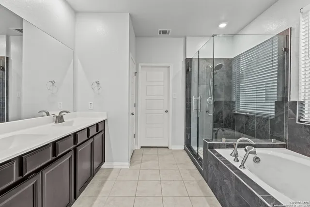 a spacious bathroom with a tub sink shower and mirror