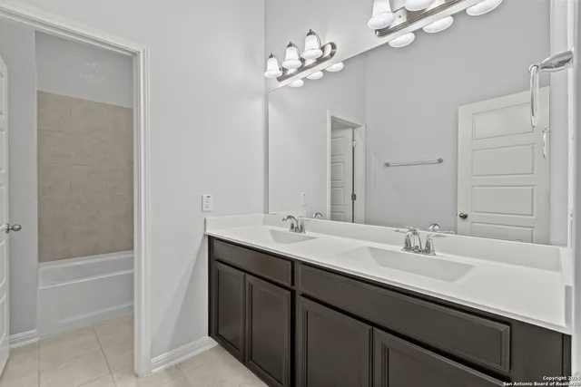 a bathroom with a sink double vanity granite tub and a mirror