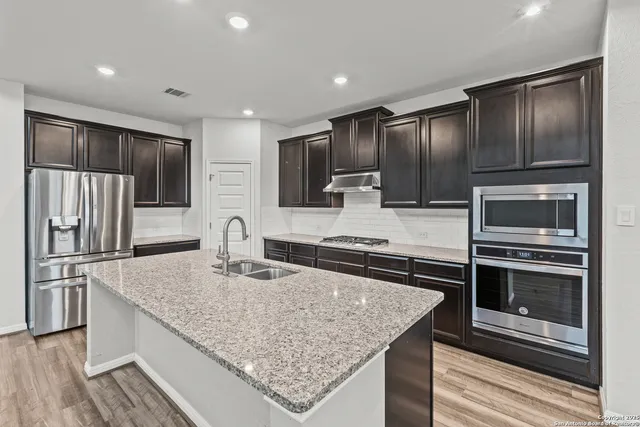 a kitchen with kitchen island granite countertop stainless steel appliances and a counter space
