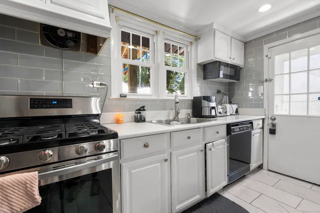 a kitchen with stainless steel appliances granite countertop white cabinets stove a sink and dishwasher