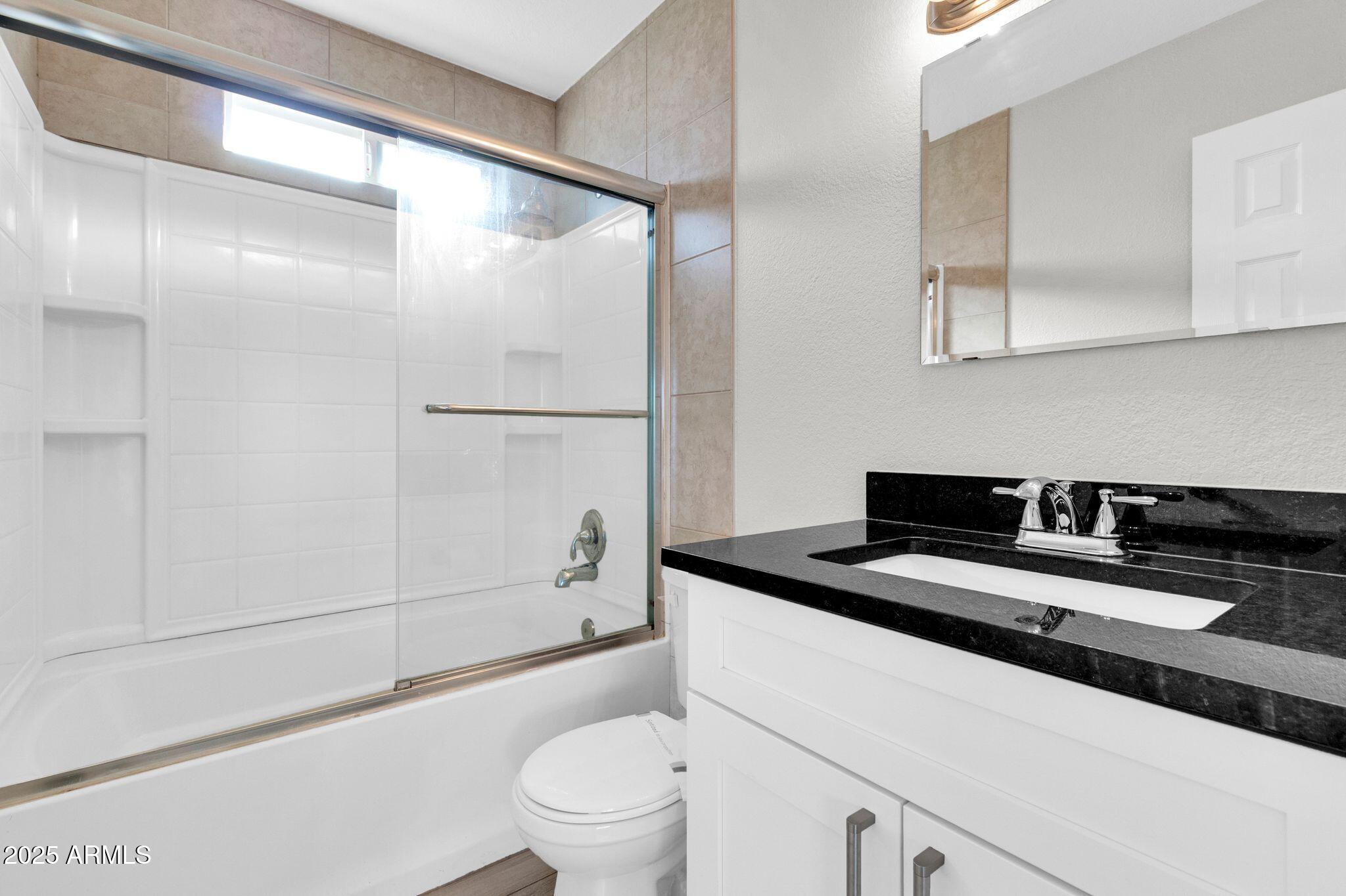 449 East Harmony Avenue Mesa, AZ 85204 - Photo 19 of 30 a bathroom with a granite countertop sink a toilet a mirror and shower