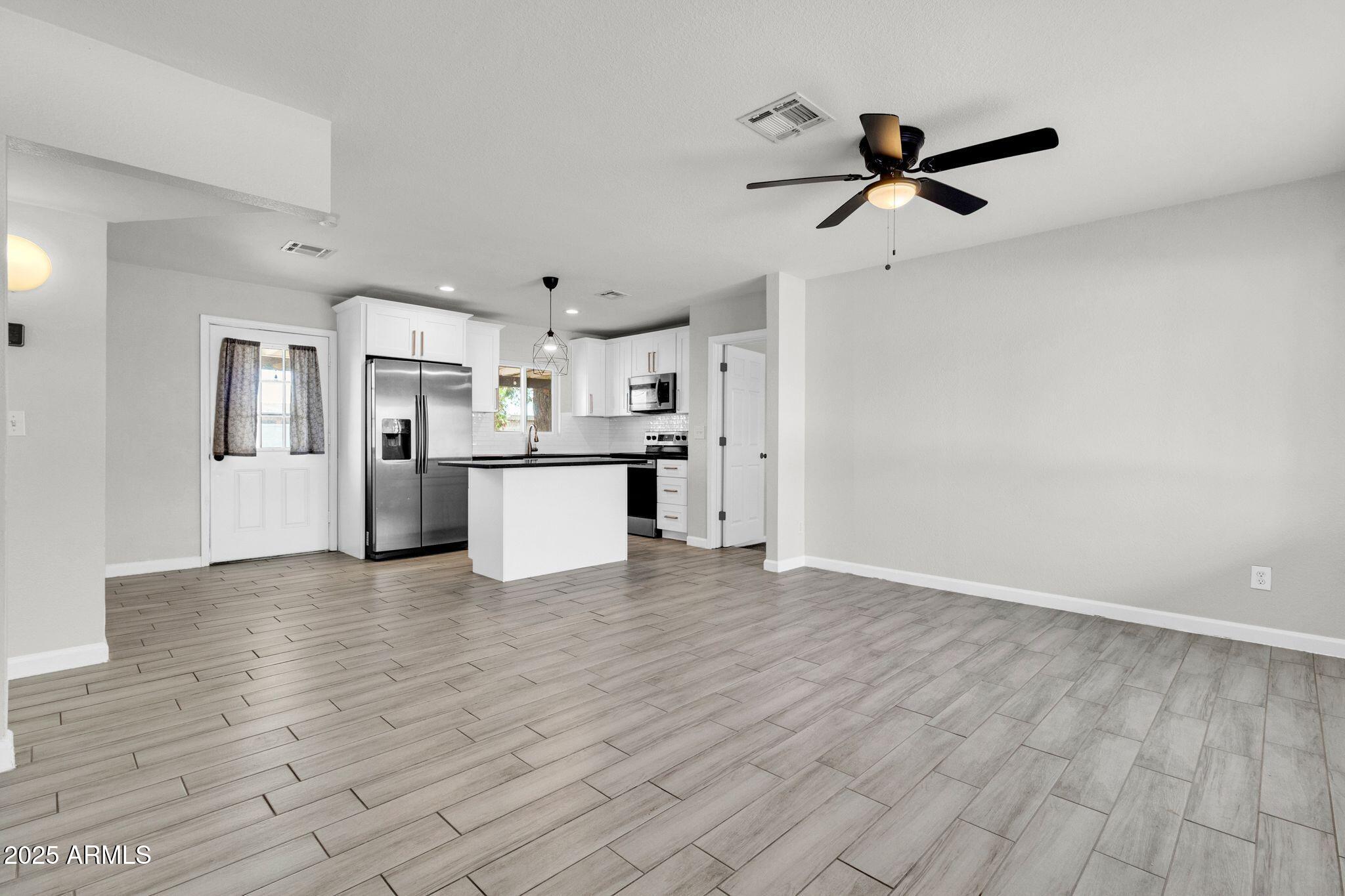 449 East Harmony Avenue Mesa, AZ 85204 - Photo 6 of 30 a view of a kitchen with a fridge wooden floor and a window