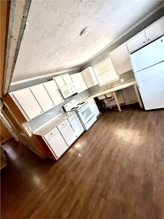 a view of an empty room with wooden floor and windows