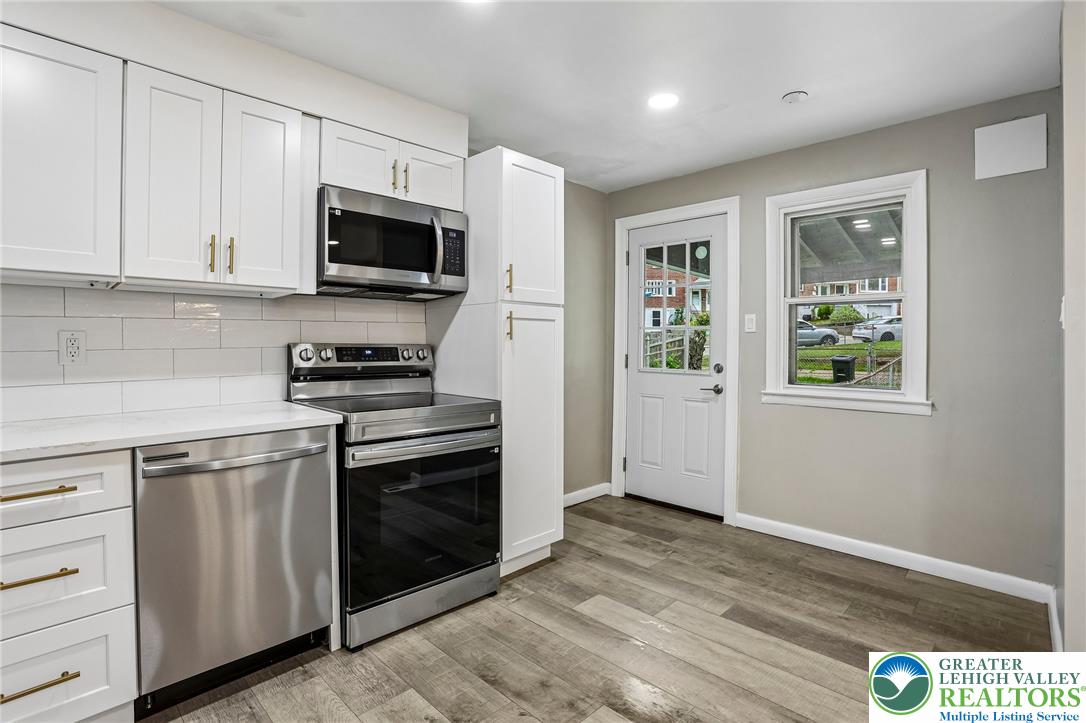 4008 Powell Road Brookhaven, PA 19015 - Photo 13 of 36 A contemporary kitchen showcasing stainless steel appliances, crisp white cabinetry, and durable wood-look flooring.