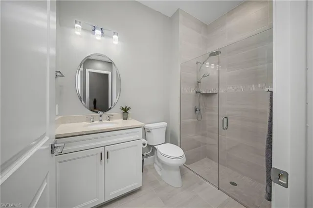 a bathroom with a toilet sink vanity granite and shower