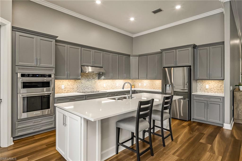 17574 Ashcomb Way Estero, FL 33928 - Photo 6 of 32 a kitchen with stainless steel appliances granite countertop a stove refrigerator sink and cabinets