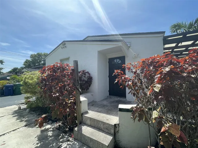 a front view of a house with lots of plants and trees