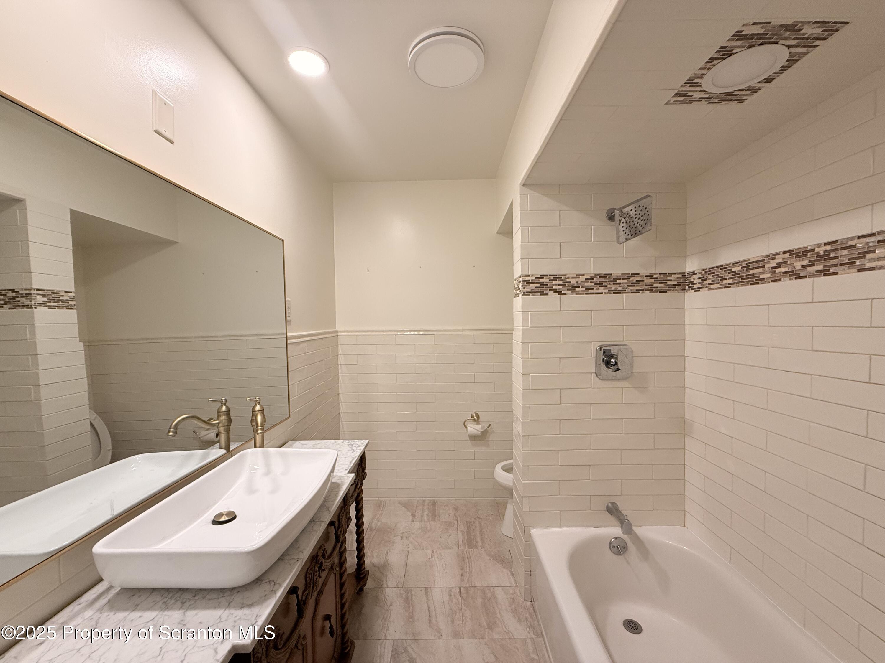 629 Clay Avenue, Unit 1 Scranton, PA 18510 - Photo 15 of 15 a bathroom with a tub a sink and a mirror