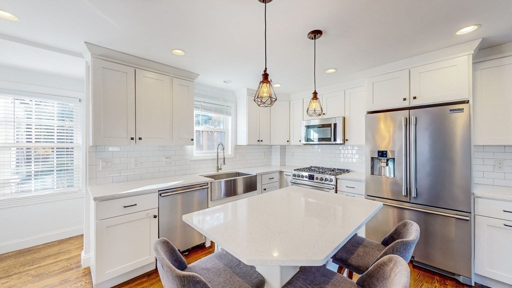 a kitchen with stainless steel appliances a refrigerator a sink a stove a dining table and chairs