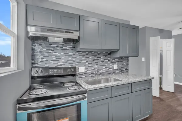 a kitchen with a stove and white cabinets