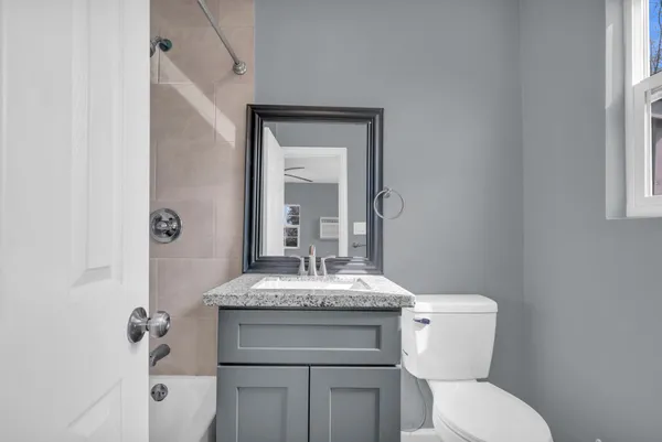 a bathroom with a granite countertop toilet sink and mirror