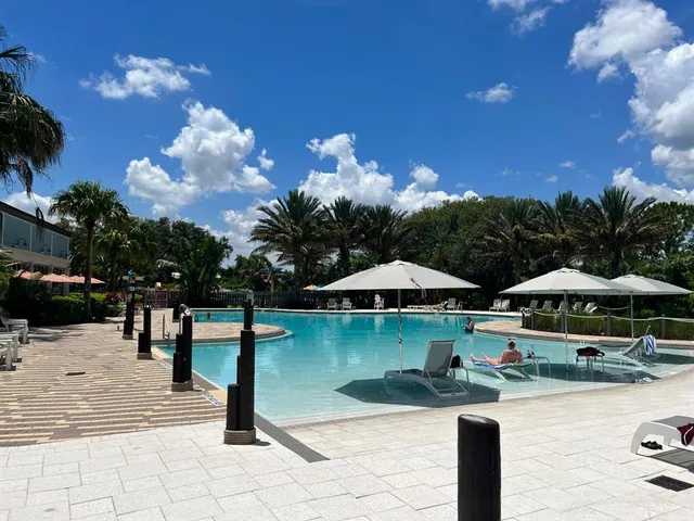 a view of swimming pool with lawn chairs under an umbrella