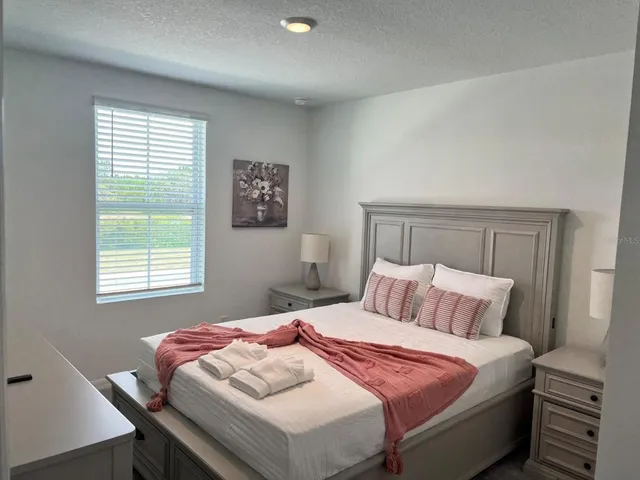 a bedroom with a bed two lamps and a window